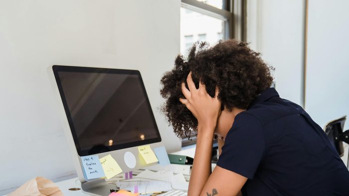 Persoon met het hoofd in de handen aan een bureau