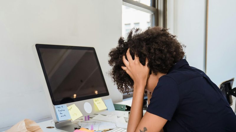 Persoon met het hoofd in de handen aan een bureau